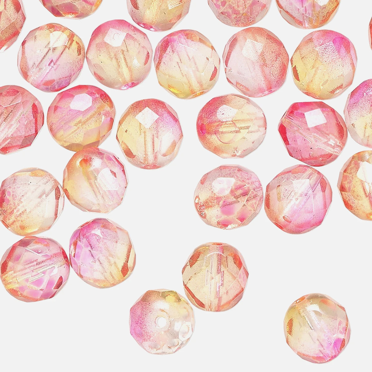 Faceted round craft beads with a pink, peach, and yellow iridescent finish scattered on a light gray background.