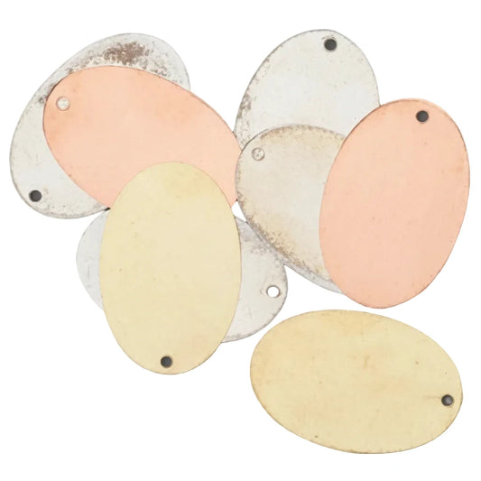 Six oval blank metal nameplates in various colors including pale yellow, peach, and silver, arranged on a solid dark gray background.