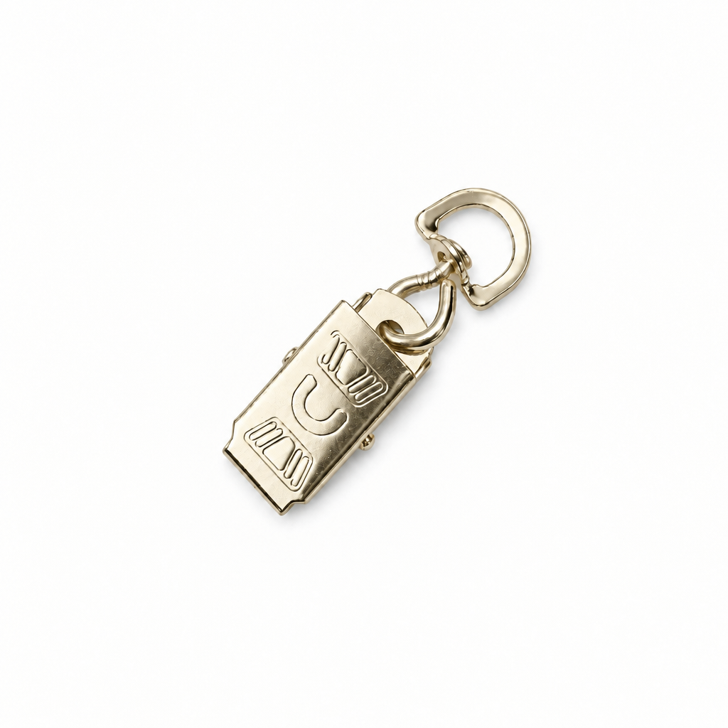 A polished gold BRASS rectangular pendant charm with engraved lettering, attached to a matching gold split ring and loop, shown on a plain white background.