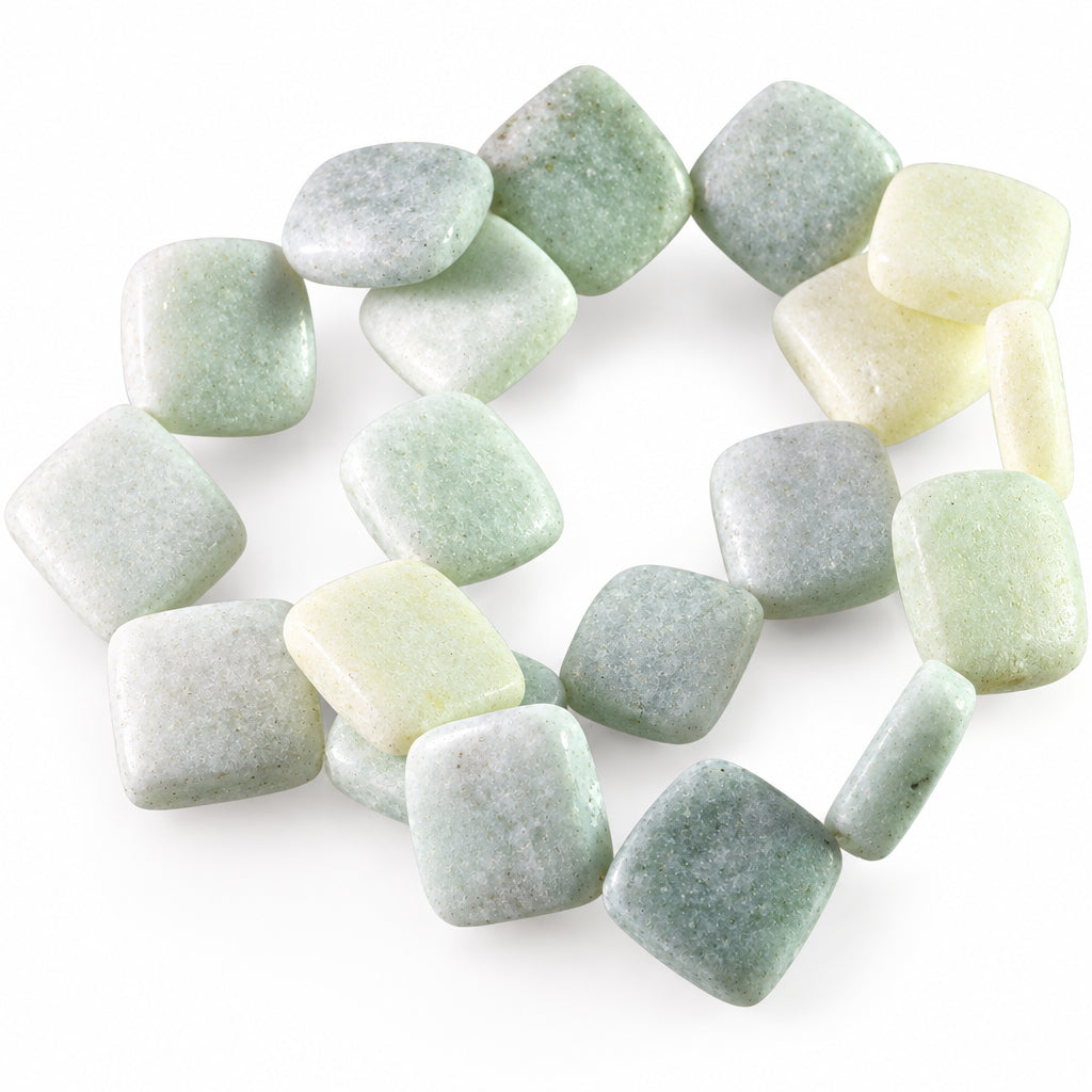 A pile of polished, rounded square gemstone beads in pale green, white, and light gray, arranged on a clear plastic tray against a white background.
