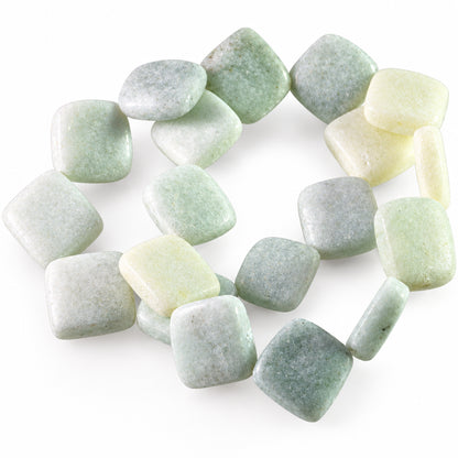 A pile of polished, rounded square gemstone beads in pale green, white, and light gray, arranged on a clear plastic tray against a white background.
