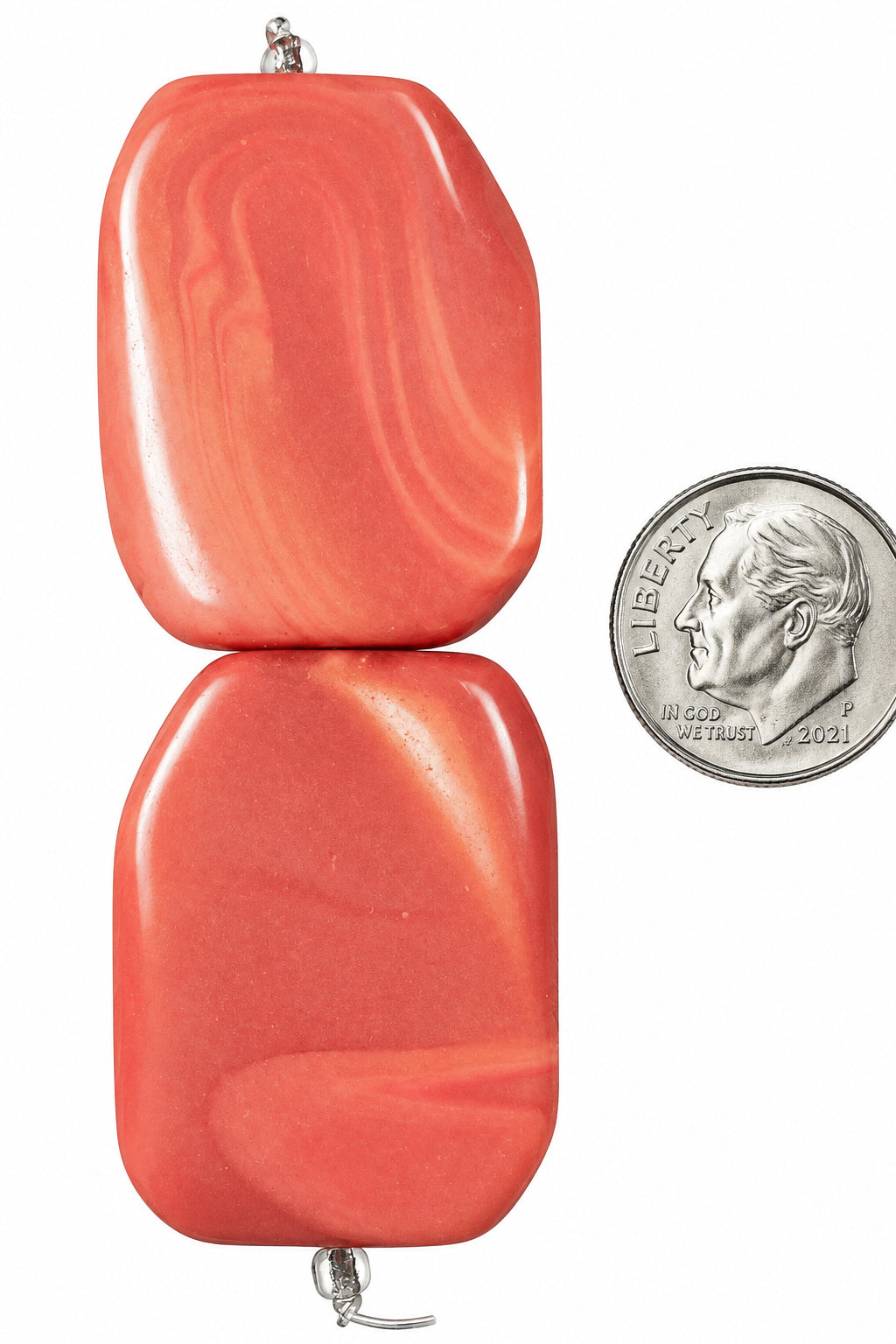 Two orange-red polished stone beads with natural marbled swirls, shown vertically with a US quarter coin for scale on a white background.