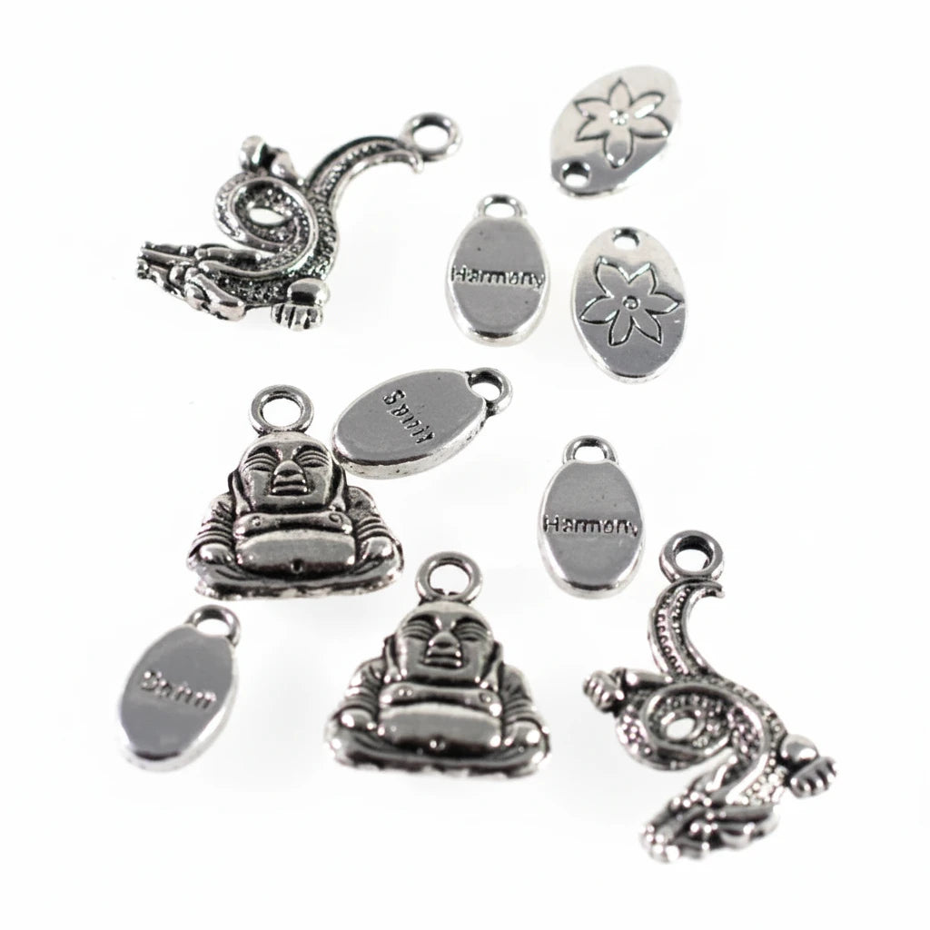 A set of silver-toned metal jewelry charms and oval tags with Buddha and dragon designs, photographed on a plain white background.