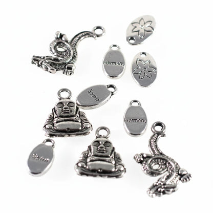 A set of silver-toned metal jewelry charms and oval tags with Buddha and dragon designs, photographed on a plain white background.