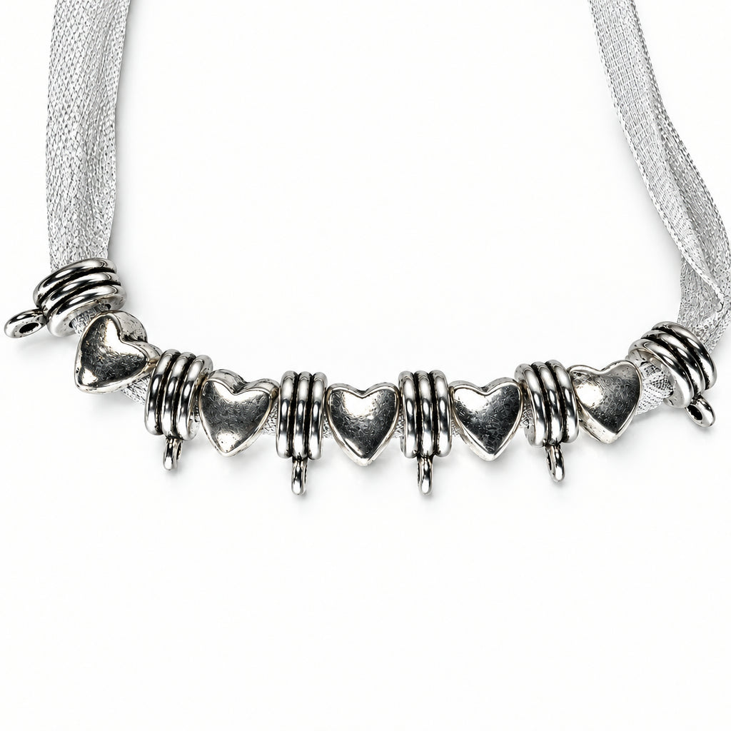 silver charm featuring heart-shaped charms and textured spiral spacers, displayed on a white ribbon against a white background.