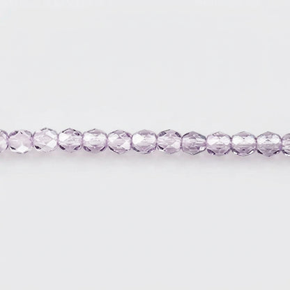 A single strand of faceted round beads in a light lavender purple color, laid horizontally against a plain white background.