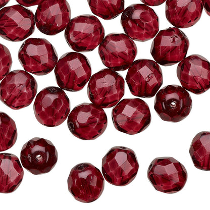 Faceted round beads in a deep burgundy red color, scattered on a plain white background.