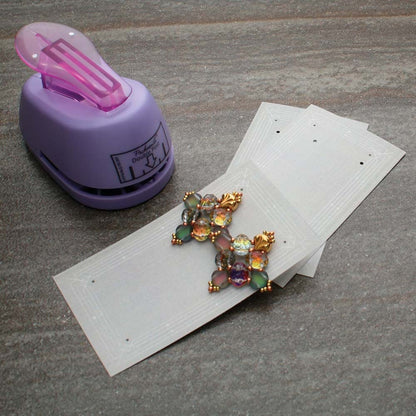 Purple paper punch with a sheet of paper and decorative letter 'K' on a gray surface