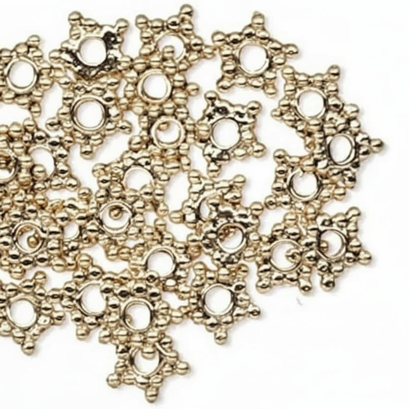 A pile of small metallic gold star-shaped jewelry findings with circular cutouts, shown on a plain white background with a single piece aligned vertically at the bottom right.