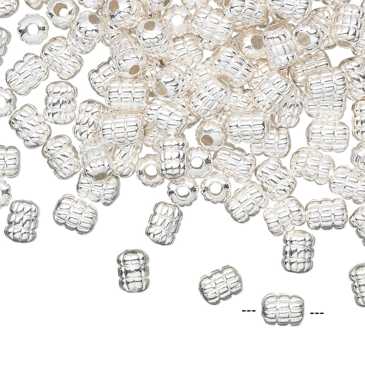 A pile of small silver spacer beads with a textured, ribbed pattern and a central hole, scattered on a plain white background.