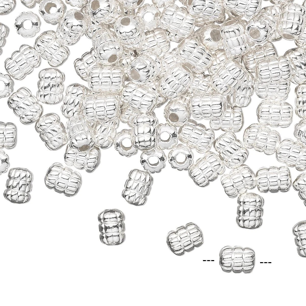 A pile of small silver spacer beads with a textured, ribbed pattern and a central hole, scattered on a plain white background.