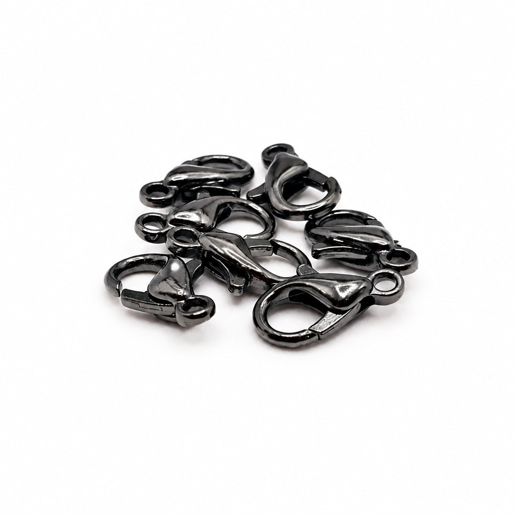 A pile of small black lobster clasp hardware pieces on a plain white background.