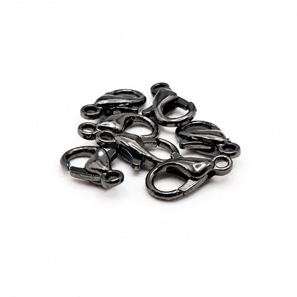 A pile of small black lobster clasp hardware pieces on a plain white background.
