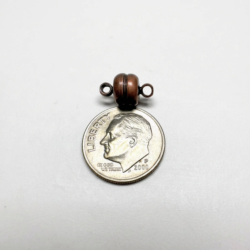 A small ANT COPPER CLASP with two metal loops on top, shown resting on a silver dime for scale against a light gray background.