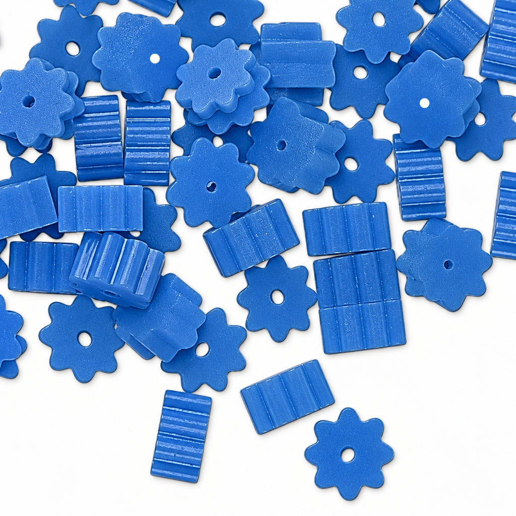 Blue plastic craft beads in flower and rectangular shapes scattered on a white background.