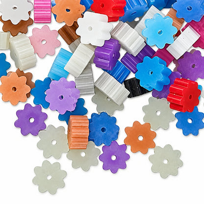 A pile of small translucent plastic flower-shaped beads in assorted pastel and bright colors, including purple, blue, red, pink, orange, white, and clear, scattered on a white background.
