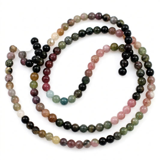 A beaded strand necklace made of faceted round gemstone beads in multiple colors including black, pink, green, brown, and white, coiled on a plain white background.