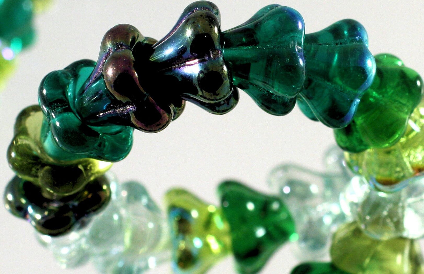Close-up of green and black glass beads on a white background