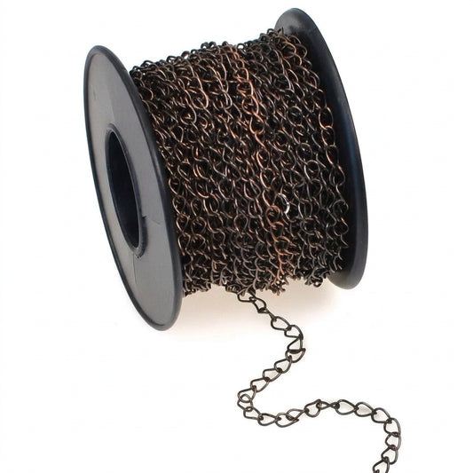 A spool of dark bronze metal chain links, with a short section of the chain draped from the bottom right, set against a plain white background.