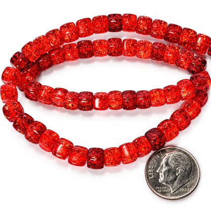 Red faceted glass beads, likely from a beaded necklace or bracelet, shown in two loops with a US quarter coin for scale on a white background.