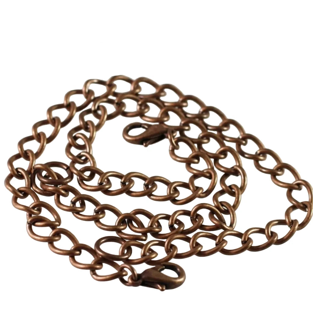 A copper-toned metal chain necklace with a lobster clasp, coiled on a white background with a ruler at the bottom for scale.