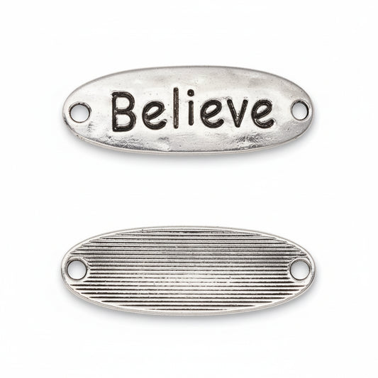 Two oval silver metal charms with holes, one showing the raised 'Believe' text on the top surface and the other showing the ribbed textured bottom, on a white background.