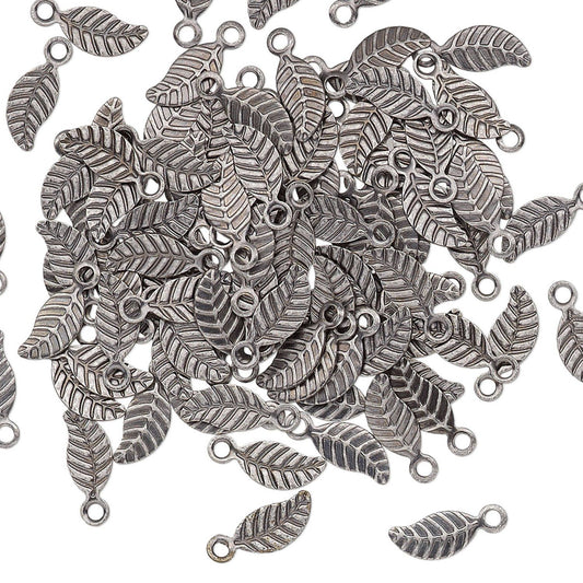 A pile of silver-toned metal leaf charms with textured veining and small loop openings, scattered on a plain white background.