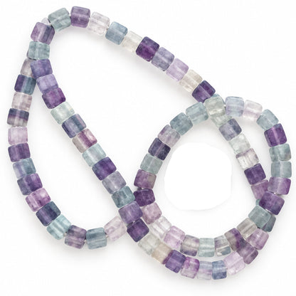 A strand of faceted cylindrical gemstone beads in a lavender, purple, blue, and clear colorway, shown with a US quarter coin for scale on a white background.