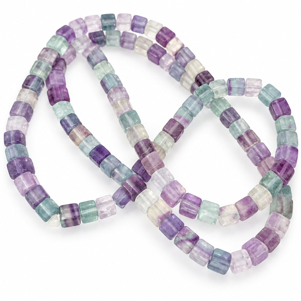 A strand of faceted rectangular beads made from natural amethyst and smoky quartz, showing a mix of purple, gray, and pale blue-green tones, arranged on a white background.