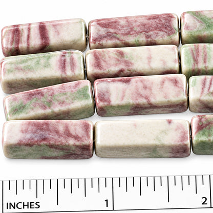 Rectangular bar beads with a marbled pattern of pink, green, and off-white, shown next to a 2-inch ruler for scale.