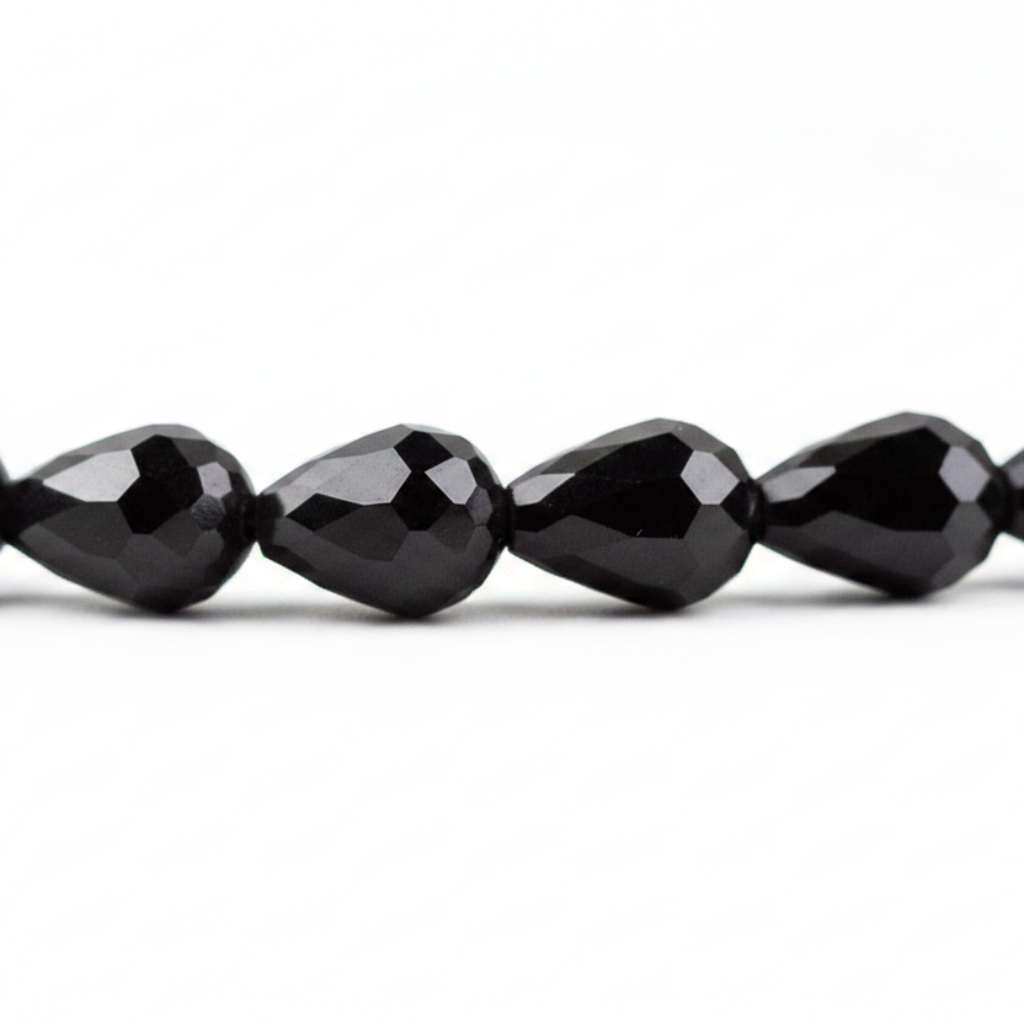 Faceted black teardrop beads strung together on a white background.