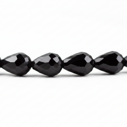 Faceted black teardrop beads strung together on a white background.