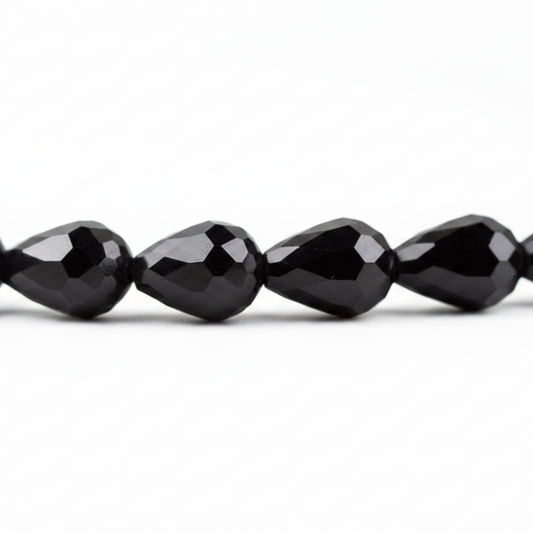 Faceted black teardrop beads strung together on a white background.