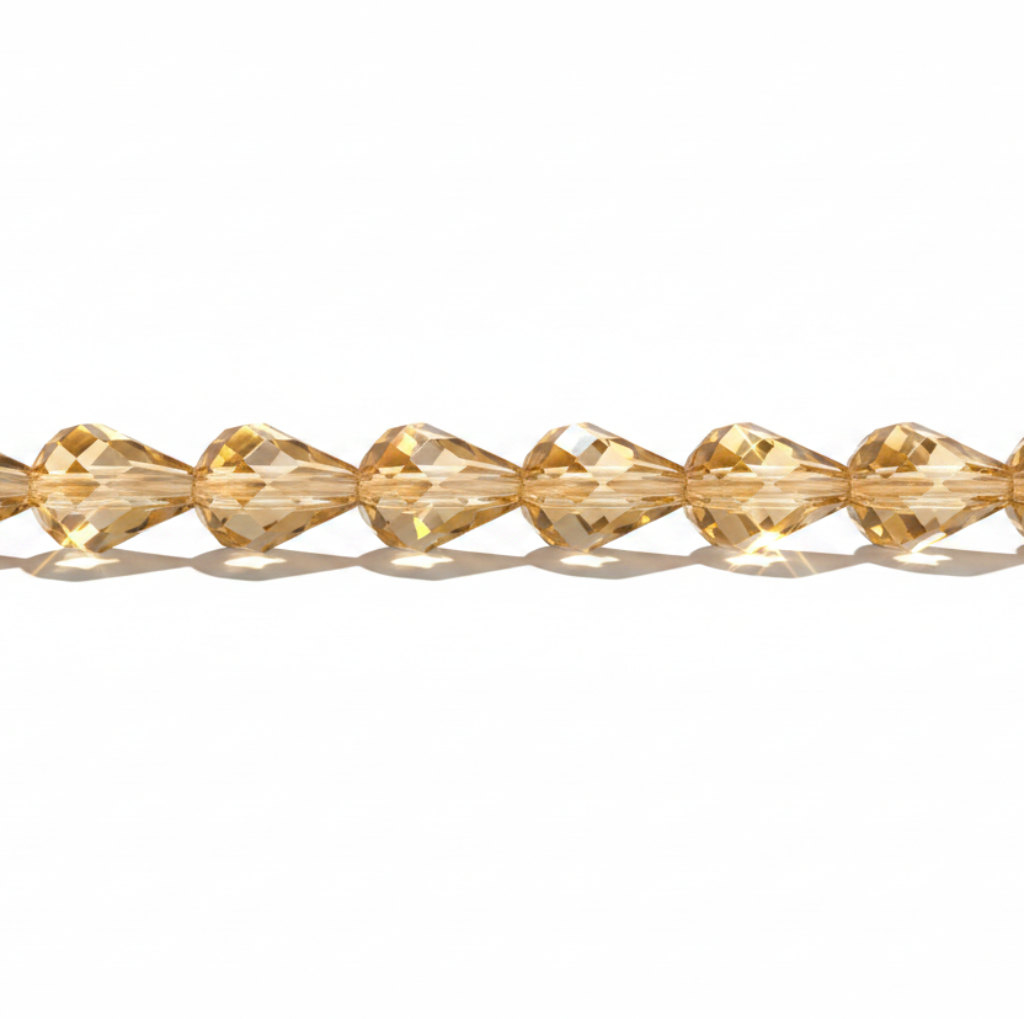 A strand of faceted, teardrop-shaped crystal beads in a warm golden-yellow color, arranged horizontally on a clean white background.