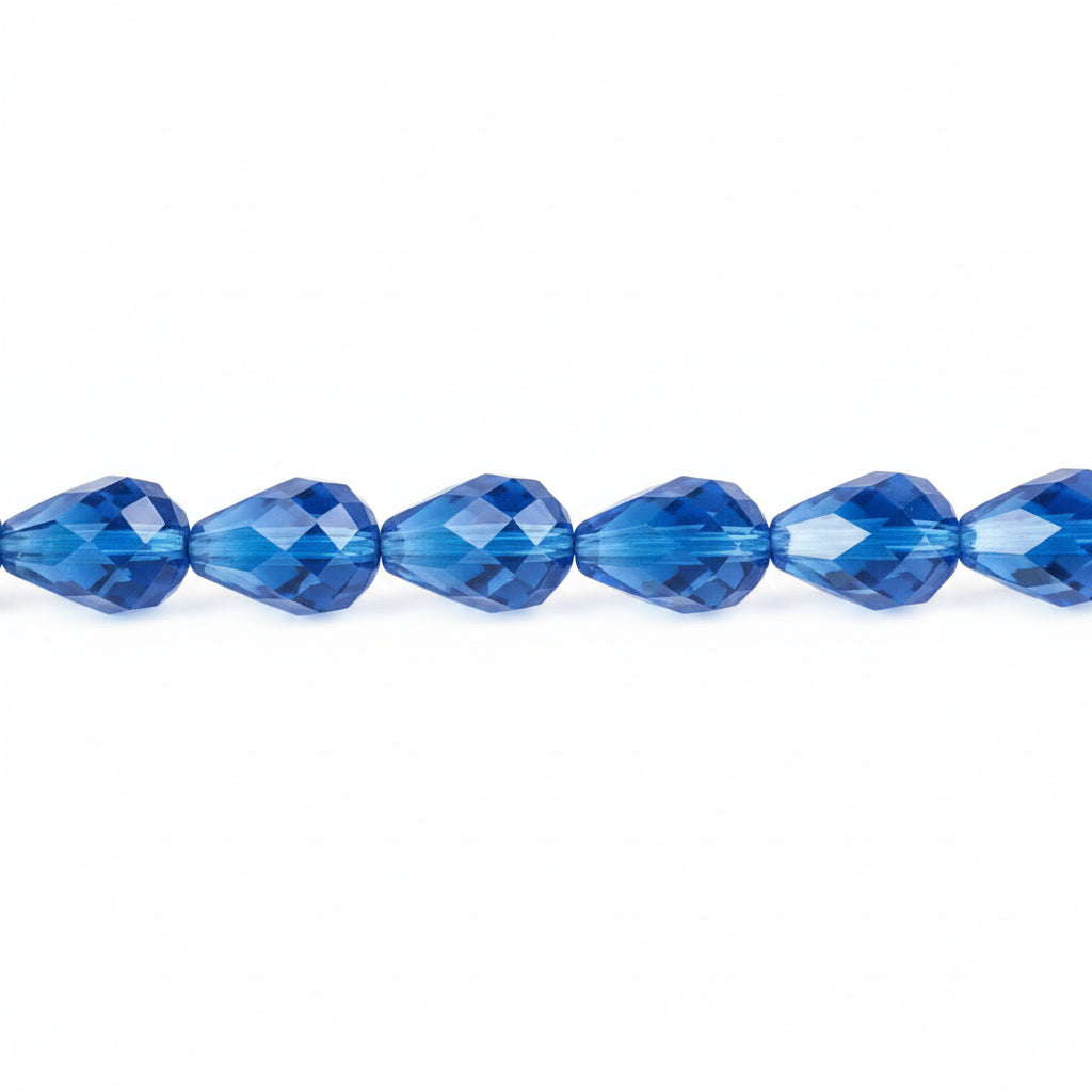 A close-up of faceted blue glass beads strung horizontally on a plain white background.