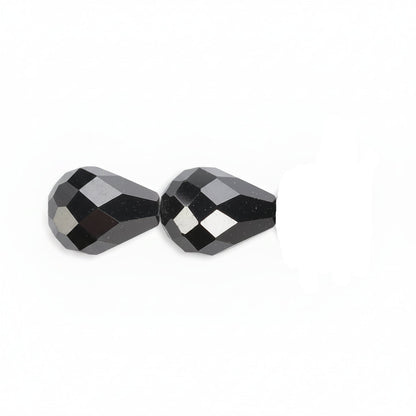Faceted black glass beads shown in a close-up horizontal line on a plain white background.