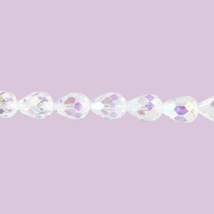 A close-up of faceted clear beads strung horizontally against a solid light lavender background.