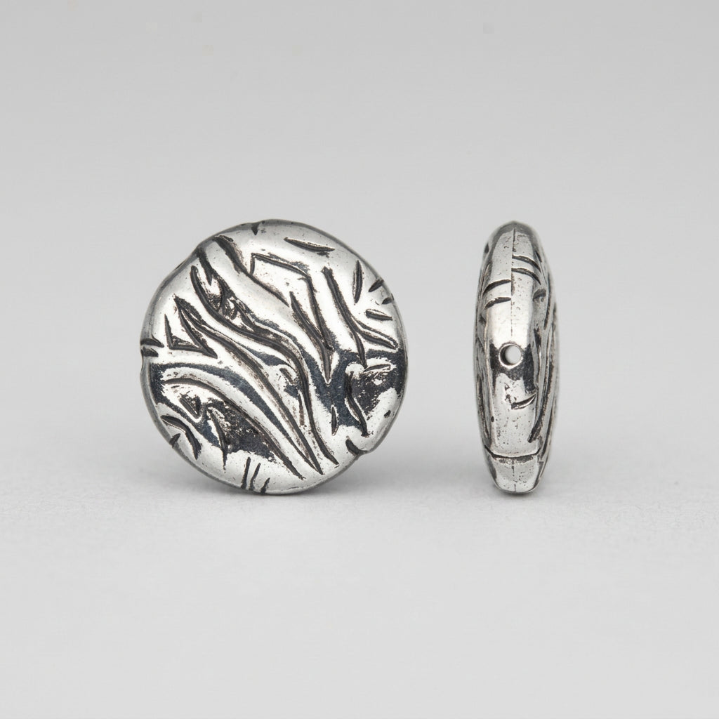 A silver-toned oval bead with a textured, engraved abstract pattern, shown from both front and side views against a plain white background.