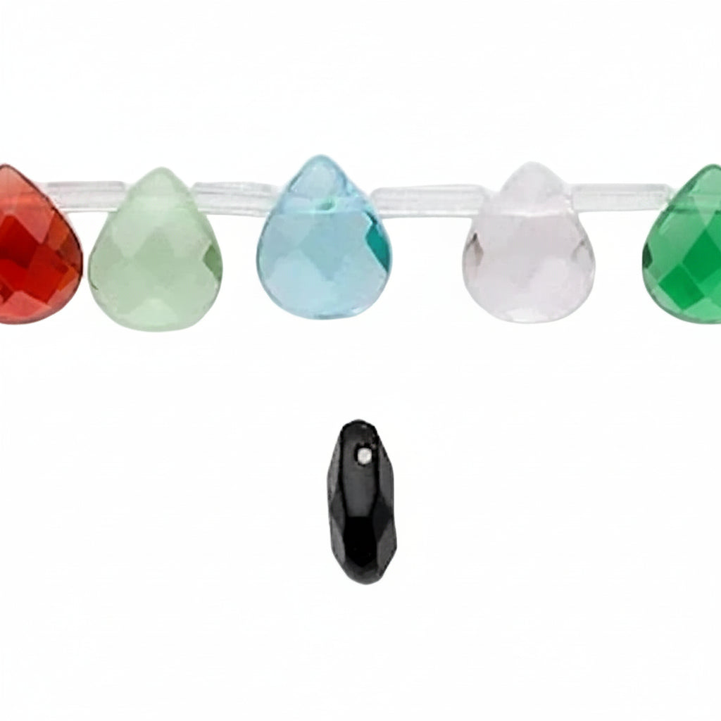 Faceted teardrop-shaped beads strung on a clear cord, shown with several colorful beads in orange, green, light blue, pale pink, and green, plus a single black bead below on a white background.