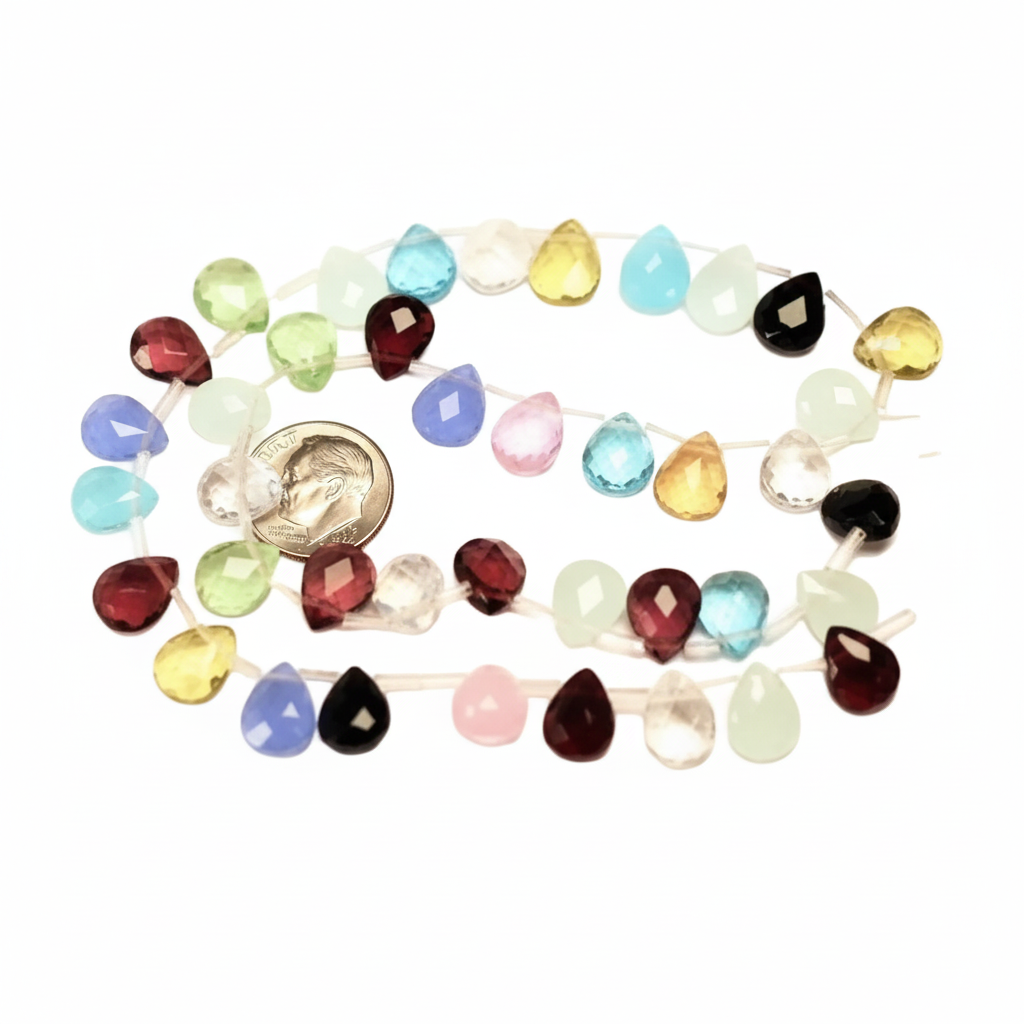 A strand of faceted teardrop-shaped gemstone beads in assorted colors, including red, blue, green, yellow, pink, black, and clear, arranged in a loose circle on a white background with a small gold coin for scale.