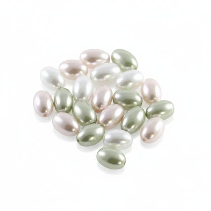 A pile of small, glossy, oval-shaped freshwater pearl beads in assorted colors including pale green, white, and soft pink, arranged on a plain white background.
