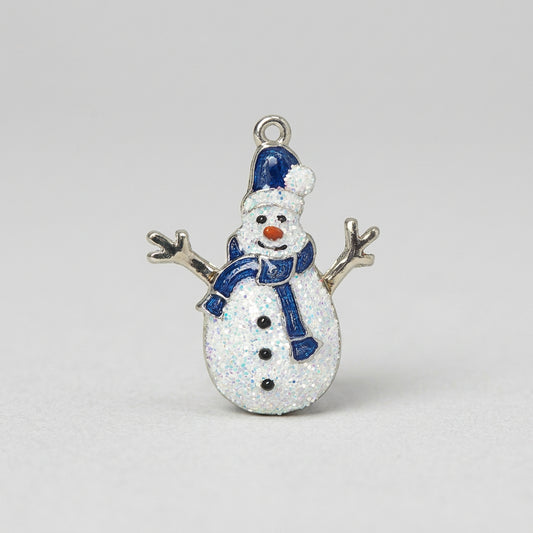 A snowman charm with a glittery white body, blue hat and scarf, and twig arms on a plain white background.