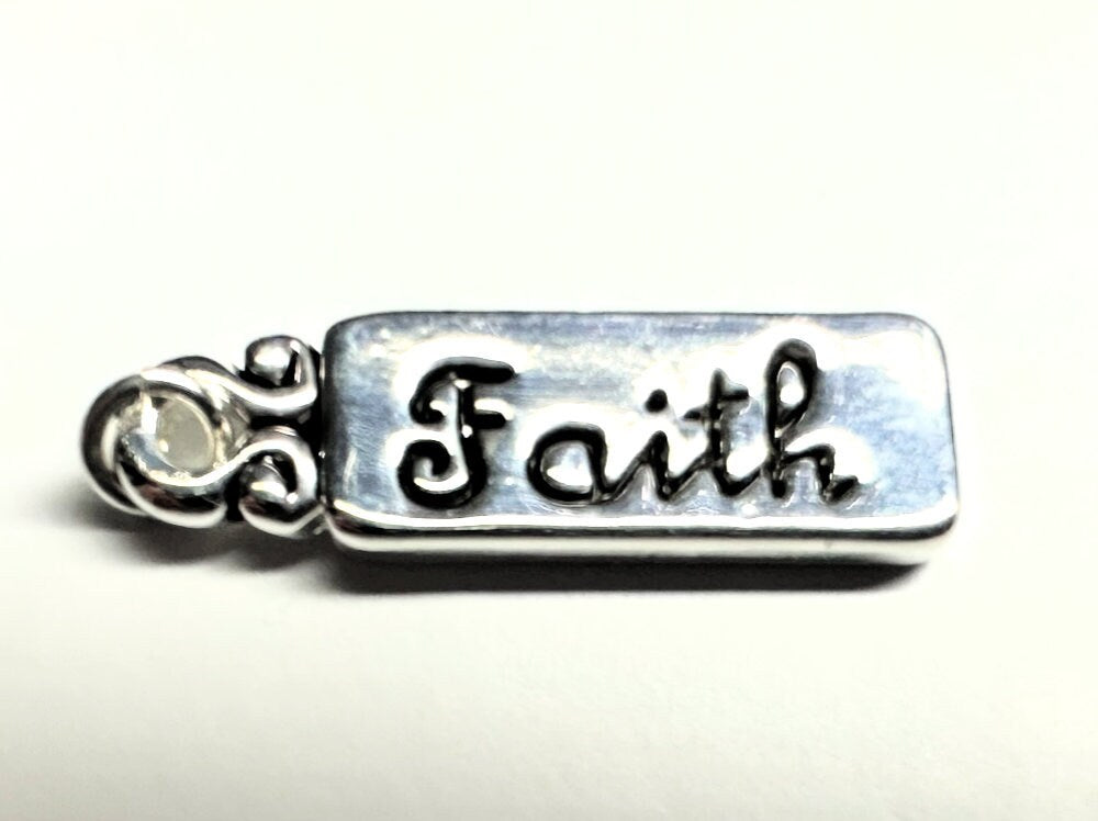 Silver charm with 'Faith' engraved on a white background
