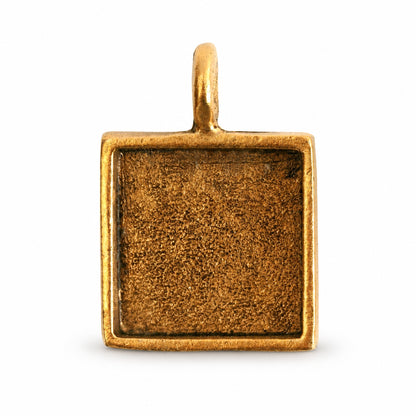 A square gold-toned metal pendant or charm blank with a textured center recess and a small top loop, shown on a plain white background.
