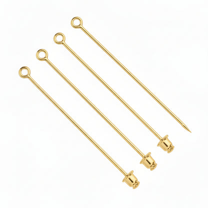 Four gold metal cocktail picks with looped ends and tapered tips, arranged diagonally on a plain white background.