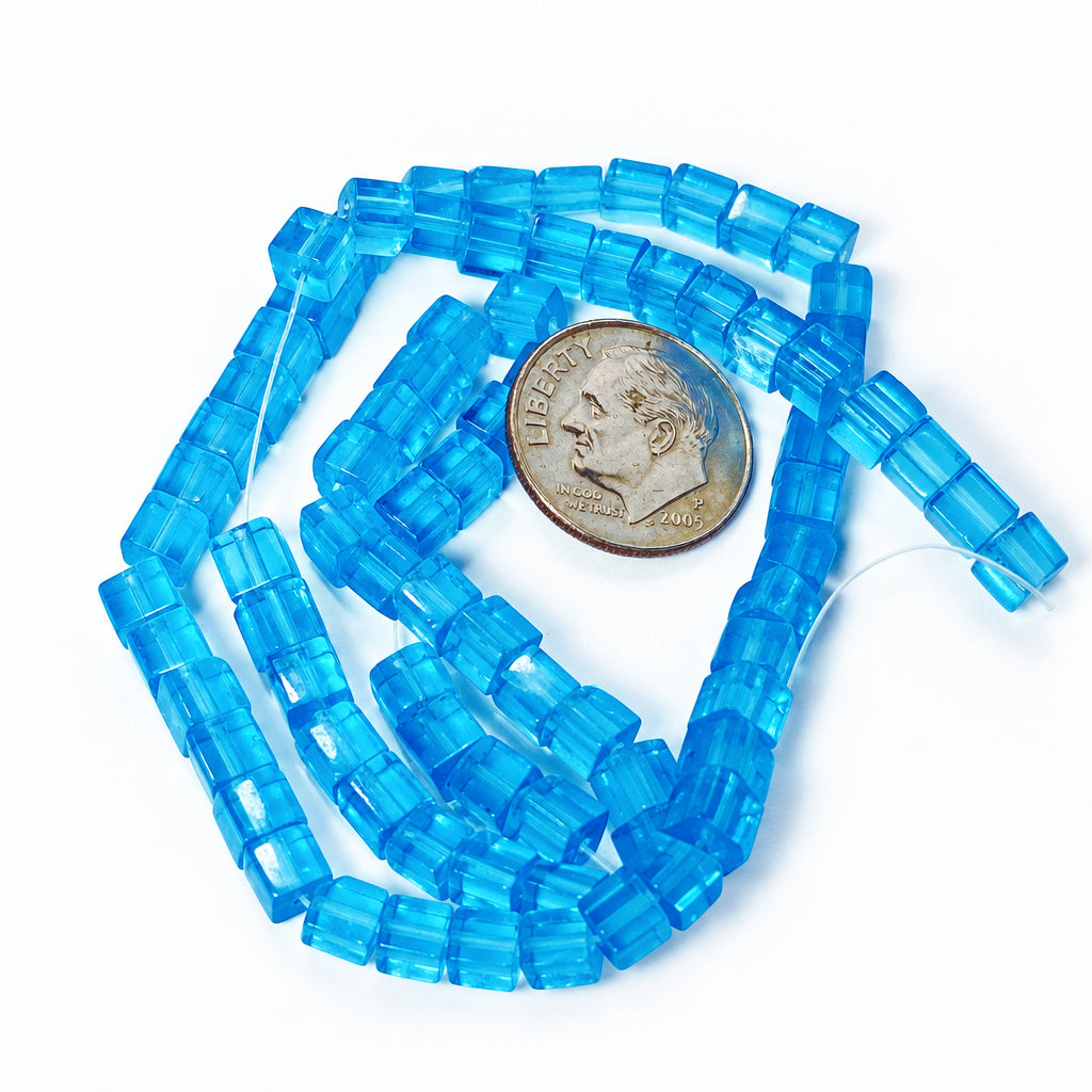 A strand of translucent blue faceted rectangular beads arranged in loops next to a U.S.