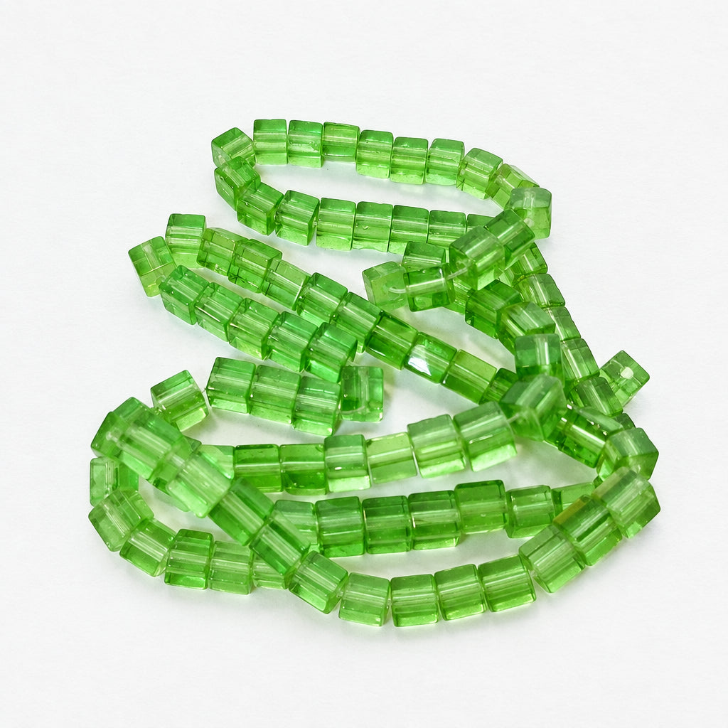 Green translucent rectangular faceted beads arranged in loose loops on a plain white background.