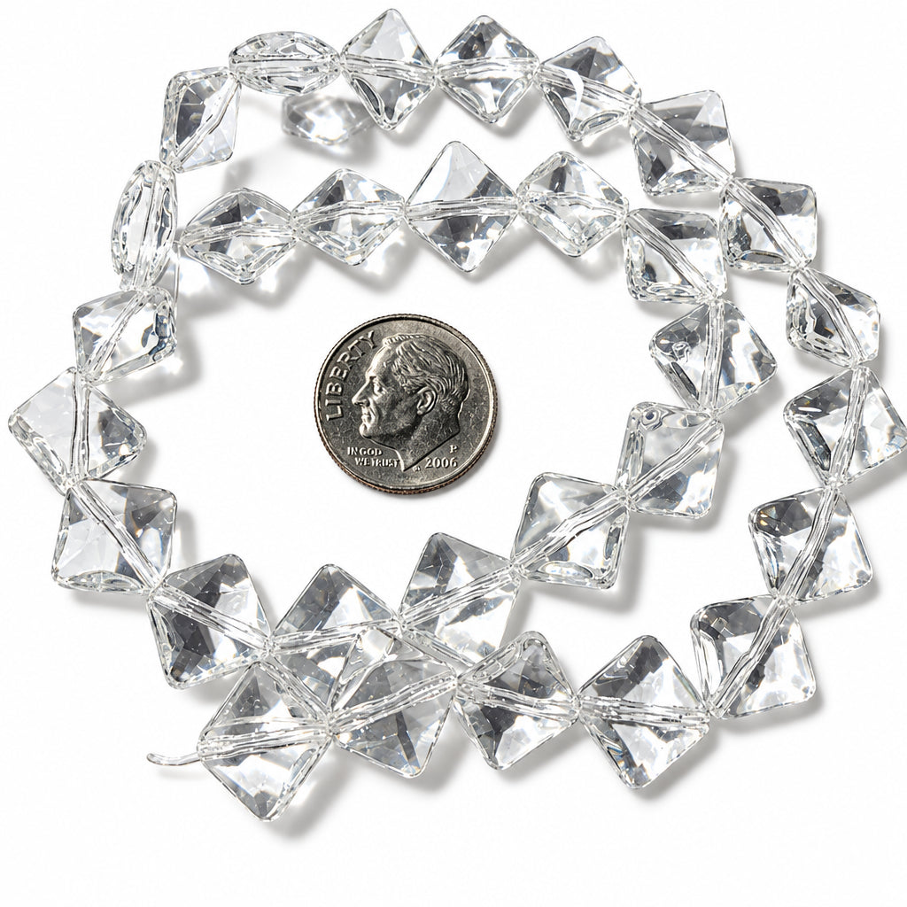 Clear faceted glass beads arranged in a loose circle on a white background, with a coin placed in the center for scale.
