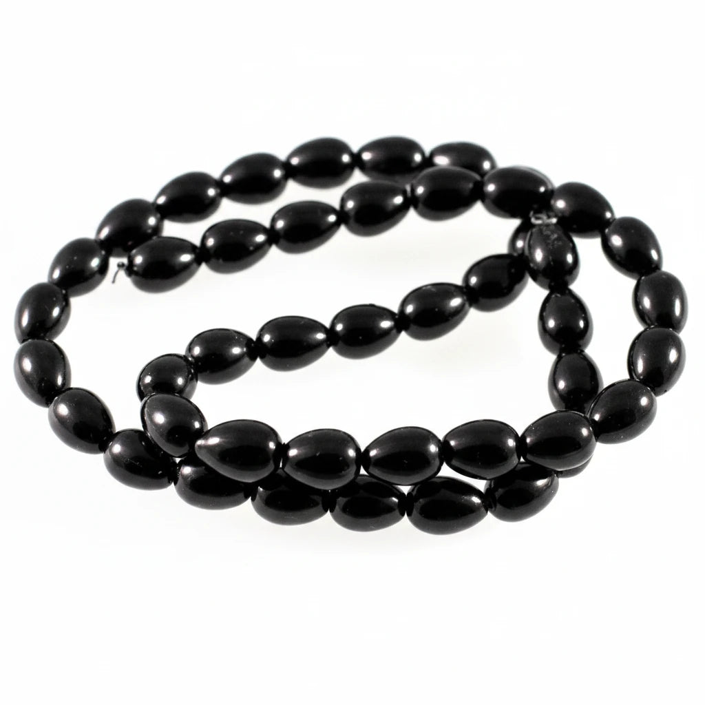 A strand of glossy black teardrop-shaped beads, likely onyx or black jasper, arranged in a loop on a plain white background.