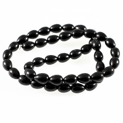 A strand of glossy black teardrop-shaped beads, likely onyx or black jasper, arranged in a loop on a plain white background.